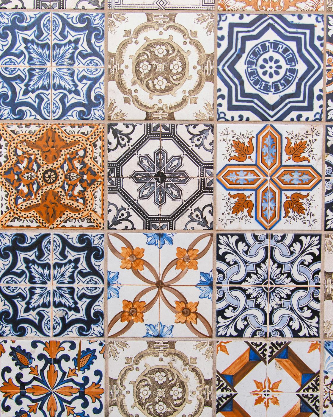 A wall of azulejos in blue, white and orange, every one a different pattern