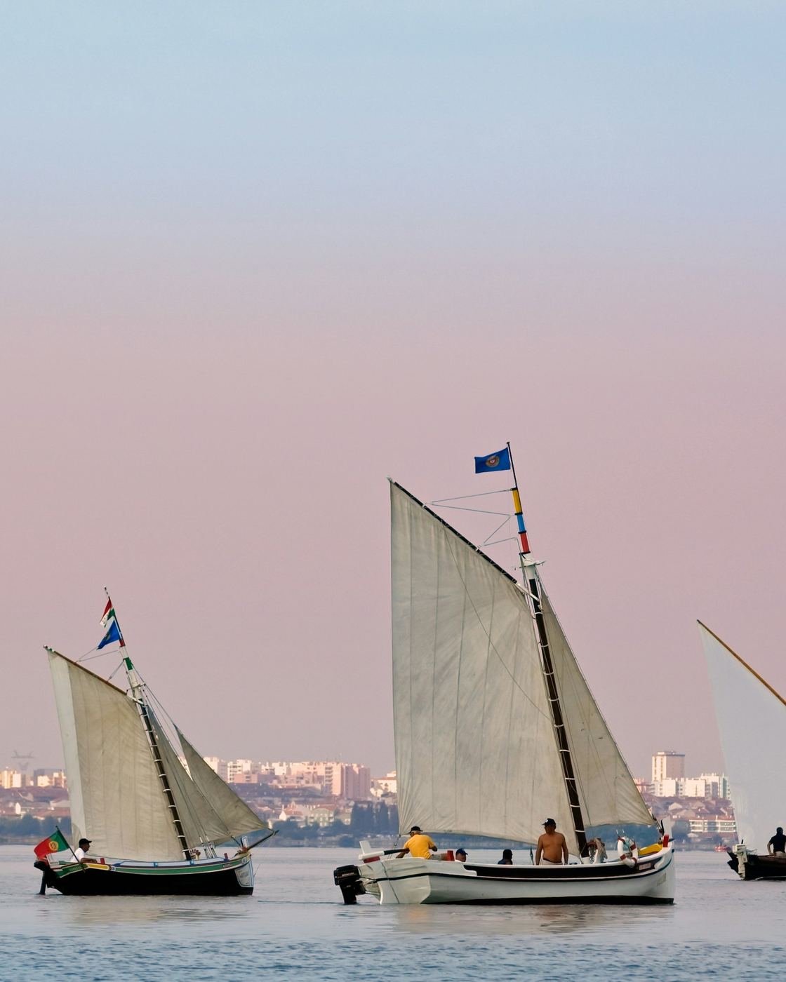 Two traditional sailing boats with tall white sails on the Tagus at dusk